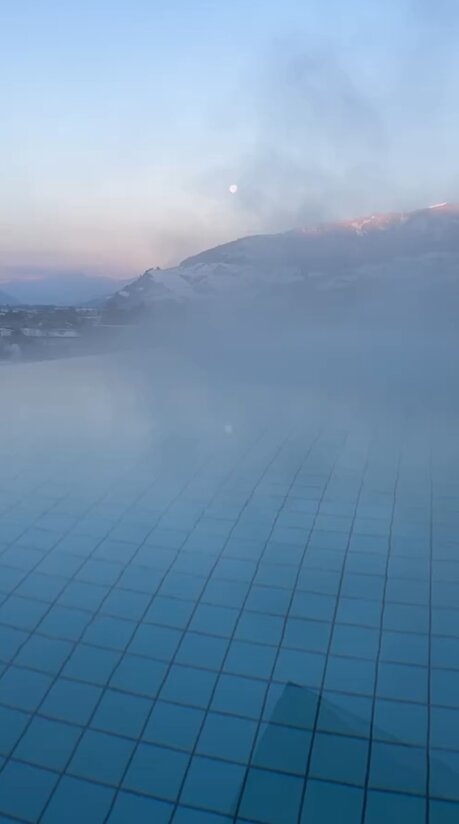 Schwimmbecken mit blauem Wasser und Nebel vor Bergkulisse