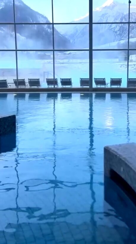 Blaues Schwimmbecken mit Liegen am Fenster in einer Therme