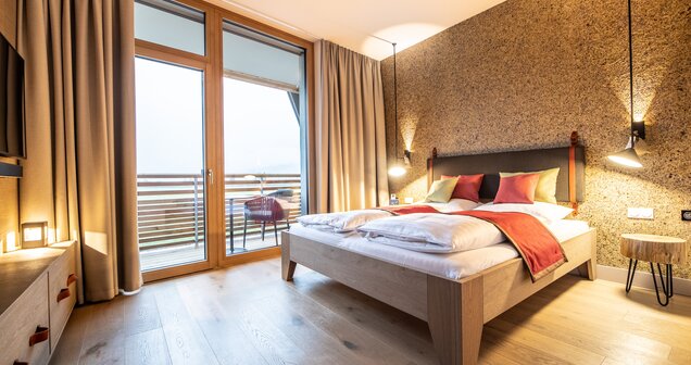 Helles Hotelzimmer mit Doppelbett, Holzboden, Balkon und gemusterter Wand