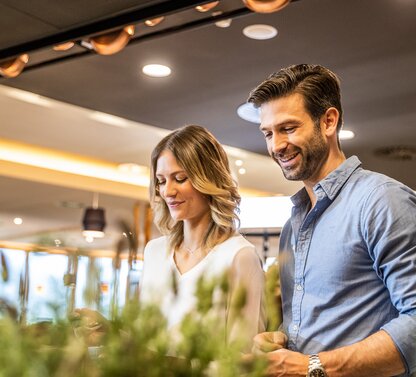 Lächelnder Mann und Frau betrachten Speisen an einem Buffet