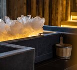 Detailaufnahme Bergkristall in dunklem Becken neben Holzeimer im Saunabereich