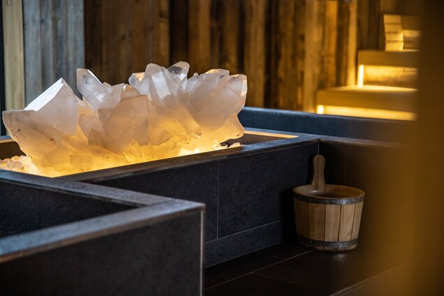 Detailaufnahme Bergkristall in dunklem Becken neben Holzeimer im Saunabereich