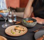 Fine food on plates and in bowls, set table with person in the background