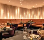Restaurant mit gedeckten Tischen, orangefarbener Eckbank und violetten Stühlen