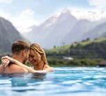 Couple hugging in the panoramic pool against a mountain backdrop