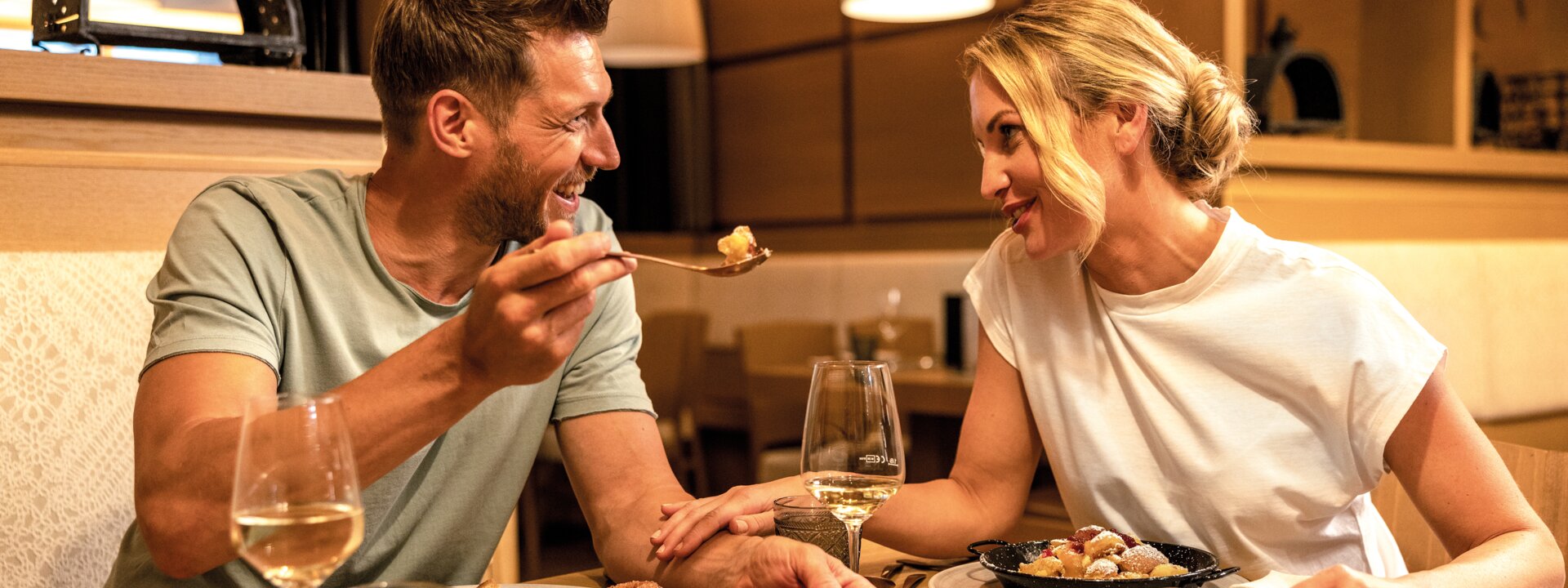 Laughing couple eating together at the table with food and wine in the Tauernstüberl restaurant