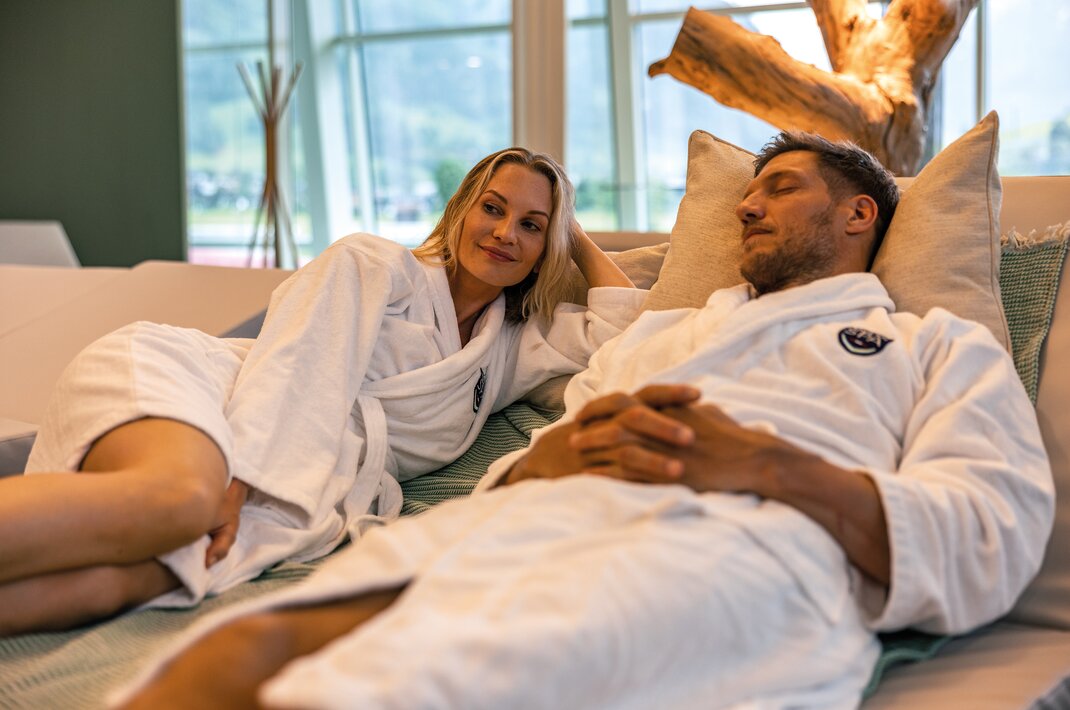 Woman and man in bathrobes relaxing on a couch
