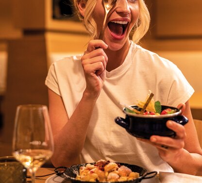Frau hält Schüssel mit Essen in der Hand und lacht