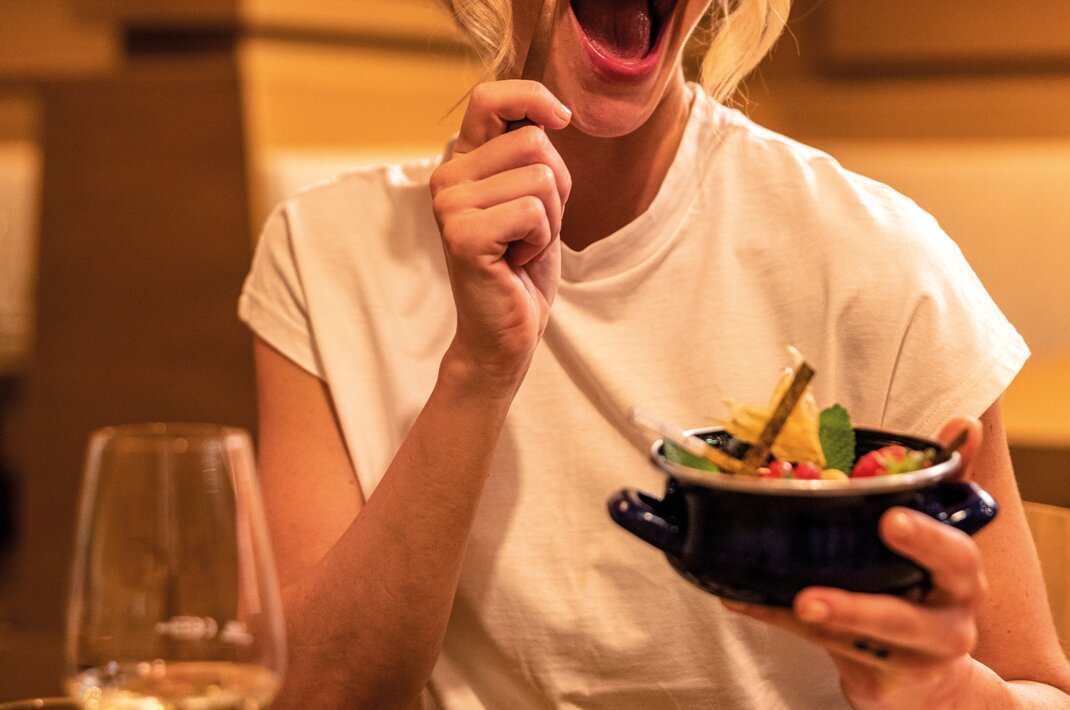 Frau hält Schüssel mit Essen in der Hand und lacht