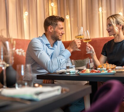 Paar prostet mit Weißwein in einem Restaurant