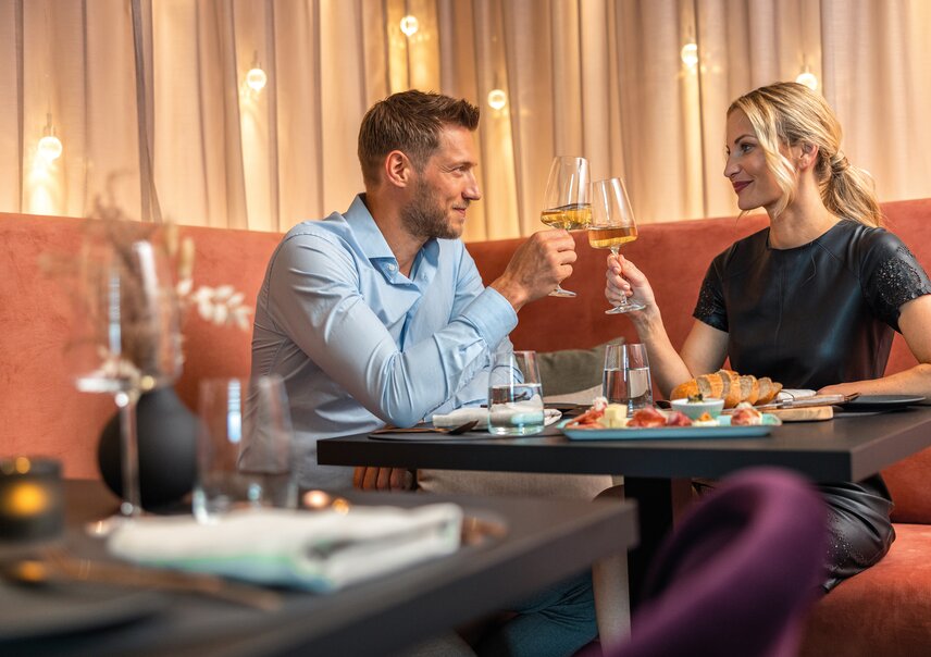 Paar prostet mit Weißwein in einem Restaurant