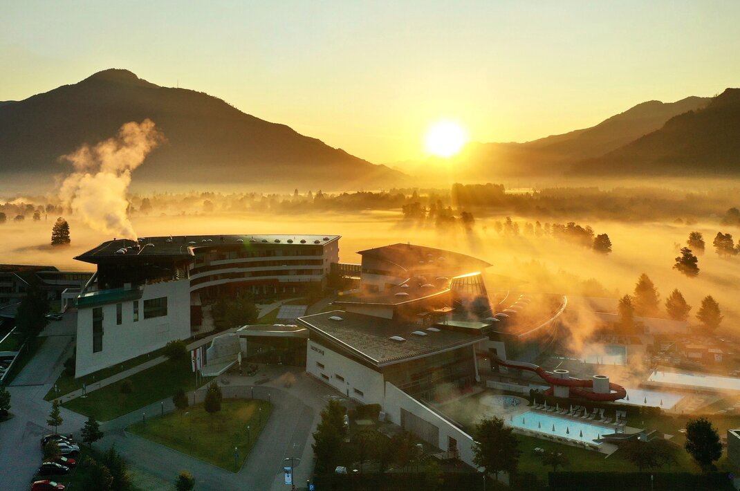 Resort im Herbstnebel bei Sonnenaufgang vor Bergkulisse
