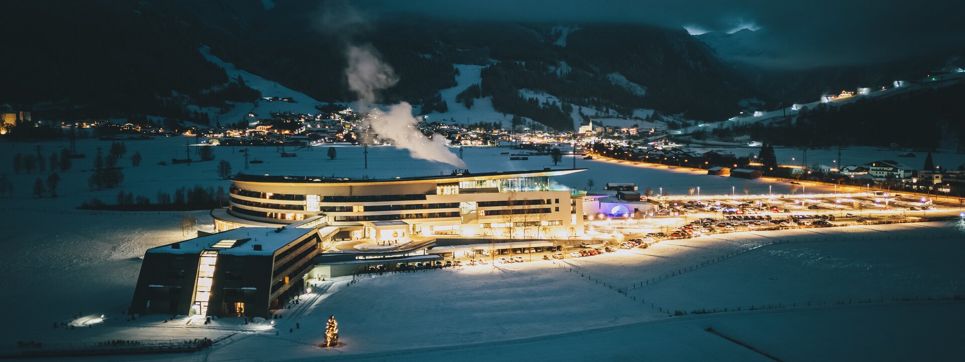 Beleuchteter Tauern SPA Gebäude im verschneiten Alpen-Tal bei Nacht