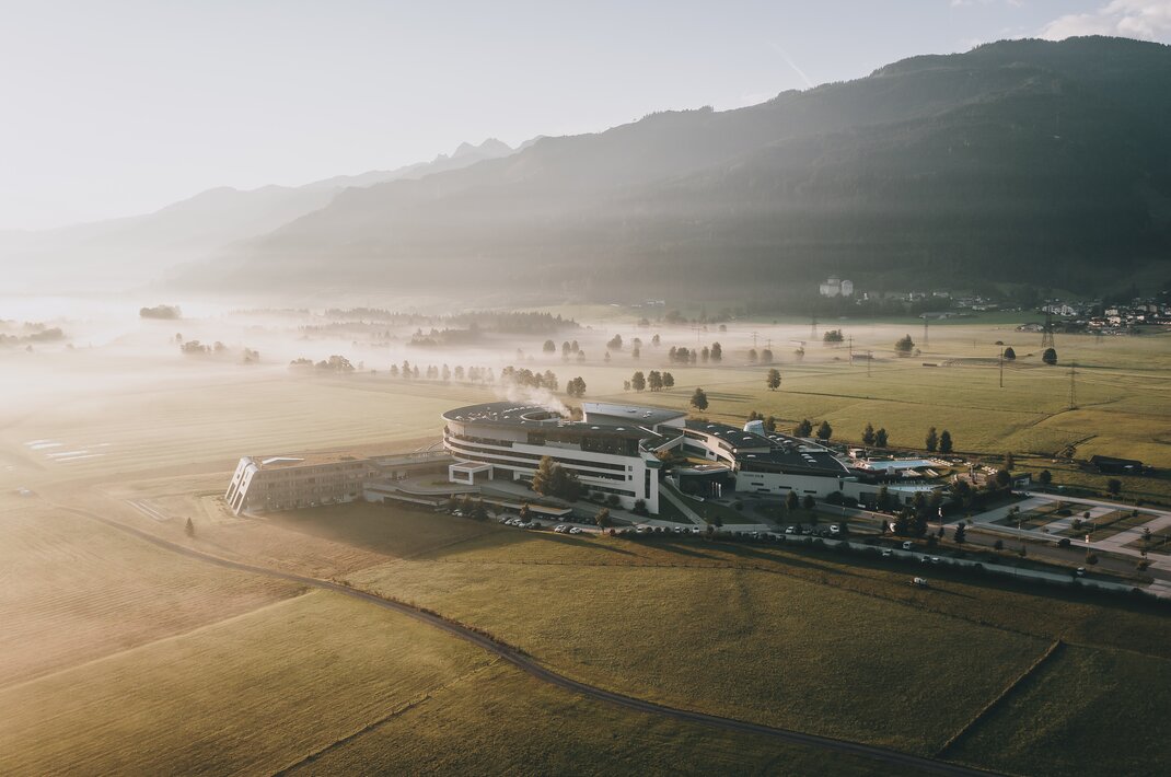 Weitläufiger Gebäudekomplex in nebliger Morgenlandschaft