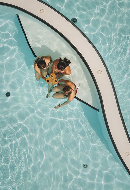 Three women toast in the pool area