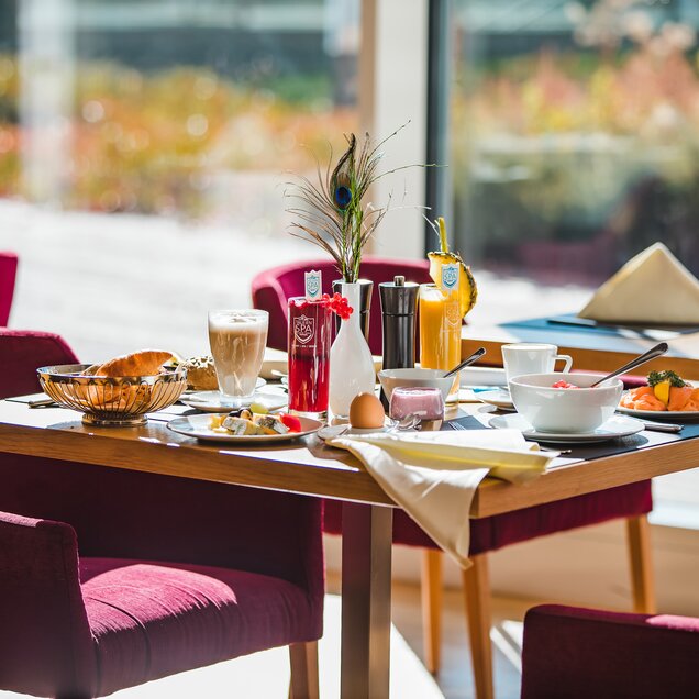 Set breakfast table with food, drinks and decoration in front of a window