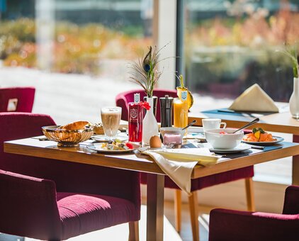 Set breakfast table with food, drinks and decoration in front of a window