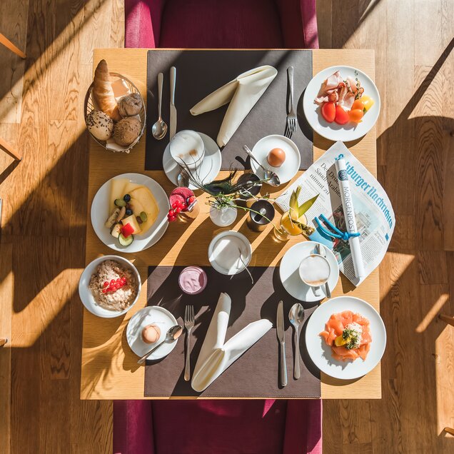 Set breakfast table with rolls, cold cuts, muesli, fruit and drinks from above