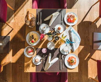 Set breakfast table with rolls, cold cuts, muesli, fruit and drinks from above