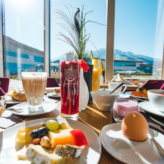 Set breakfast table with drinks, fruit, cheese, egg and view from the window