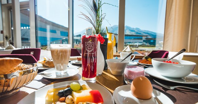 Gedeckter Frühstückstisch mit Getränken, Obst, Käse, Ei und Blick aus dem Fenster | © SPORTALPEN
