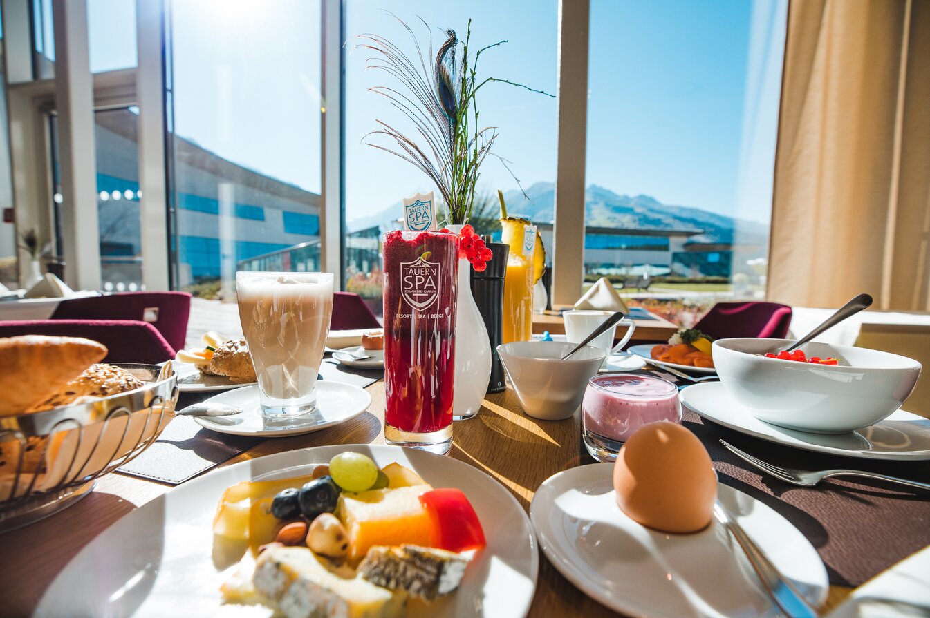 Set breakfast table with drinks, fruit, cheese, egg and view from the window