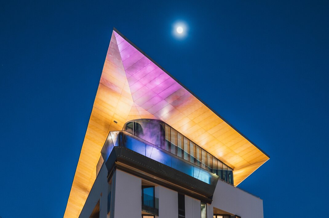 Skyline pool at night with illuminated roof under moonlight