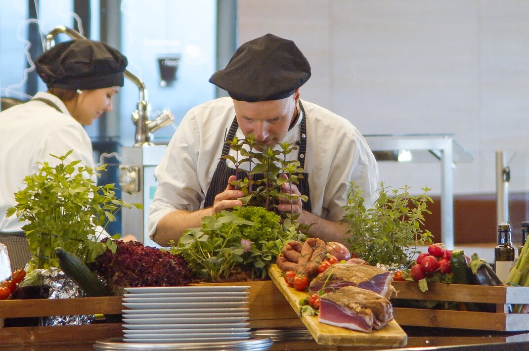 Koch beim Kräuterriechen an frischem Buffet