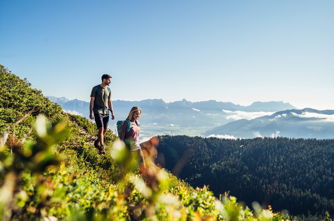 Wanderer auf Bergpfad mit Blick auf bewaldete Hügel und Tal