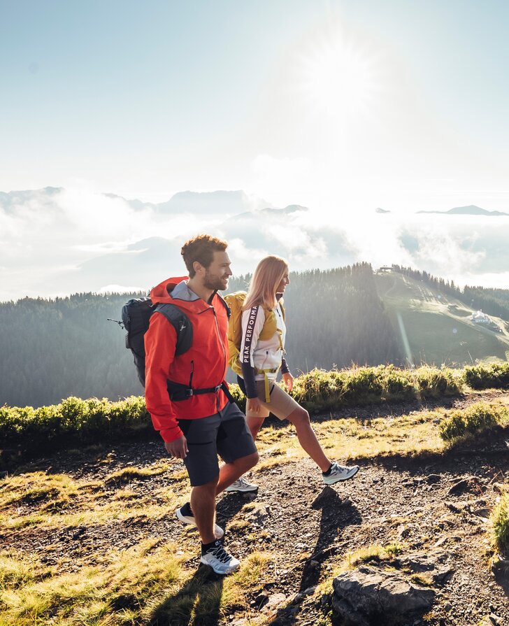 Wanderndes Paar mit Rucksack auf Bergpfad vor Bergpanorama