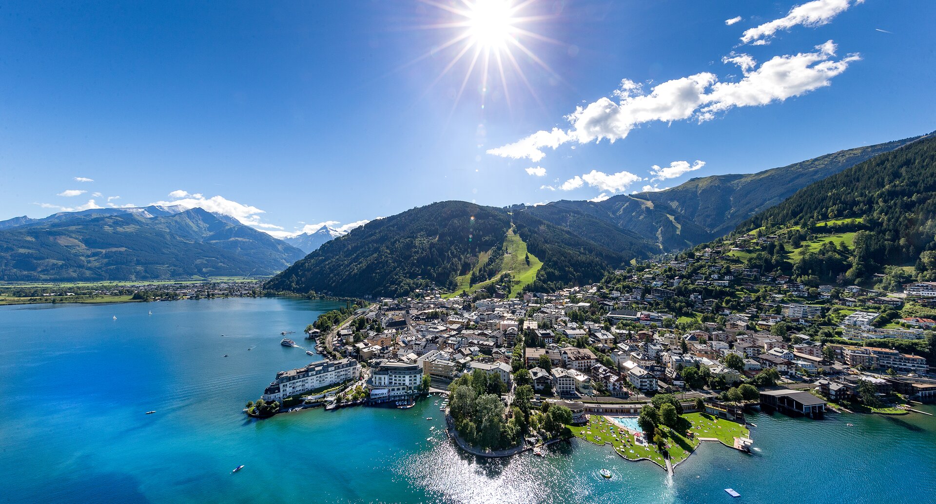 Luftaufnahme von Zell am See mit See, Bergen, Stadt und strahlender Sonne