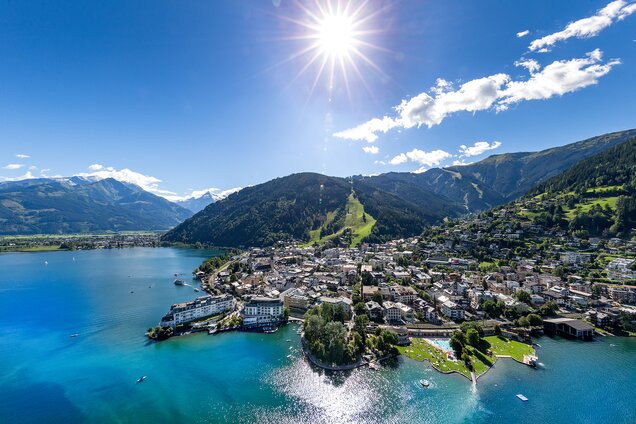 Luftaufnahme von Zell am See mit See, Bergen, Stadt und strahlender Sonne