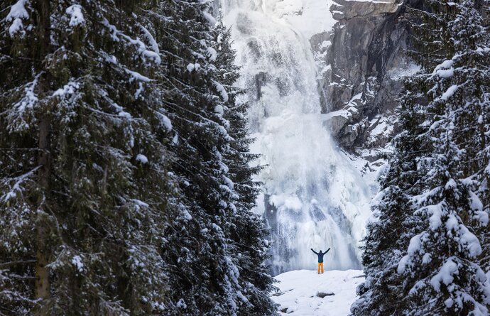 Krimmler Wasserfälle im Winter mit Person im Schnee vor dem Wasserfall