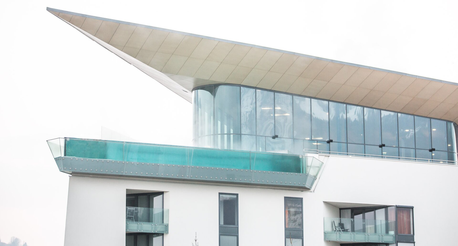 Gebäude mit Pool auf dem Dach und Glasfassade unter einem schrägen Dach