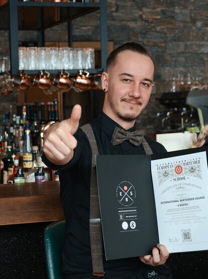 Glücklicher Barkeeper mit Zertifikat und Daumen