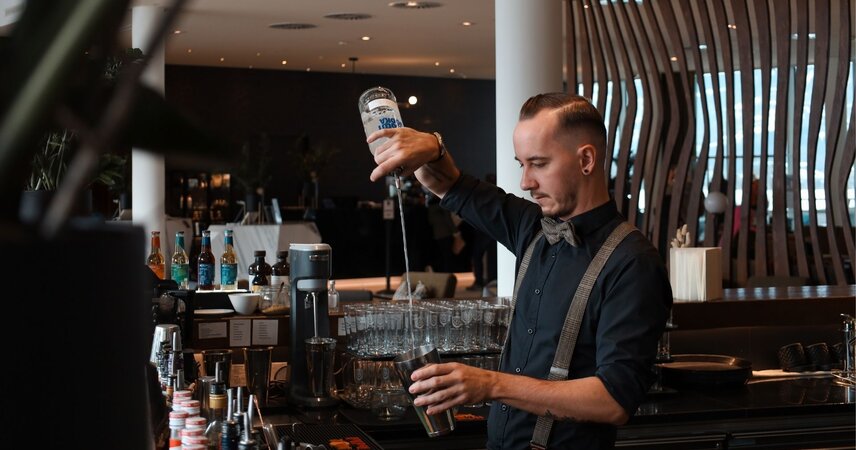 Bärtiger Barkeeper gießt Getränk in Shaker
