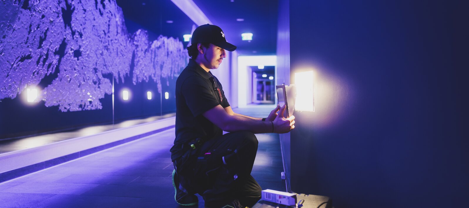 Kniender Techniker vor lila Felswandkulisse