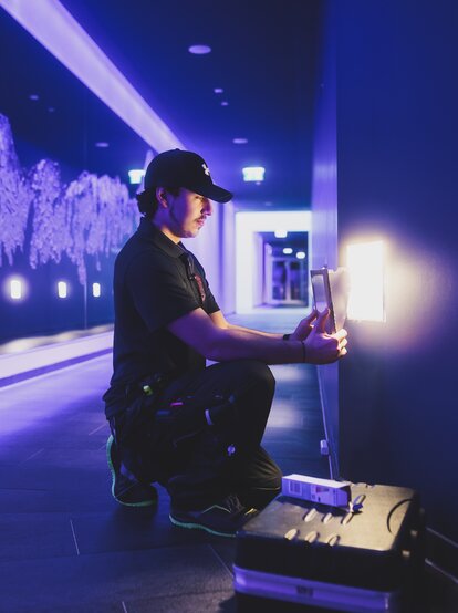 Kniender Techniker vor lila Felswandkulisse