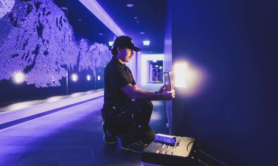 Kniender Techniker vor lila Felswandkulisse