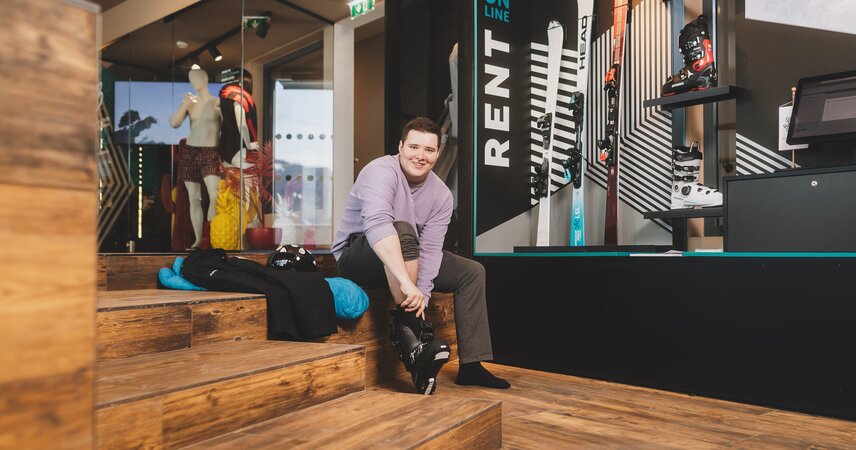 Lächelnder Mann beim Anprobieren des Skischuhs im Skiverleih