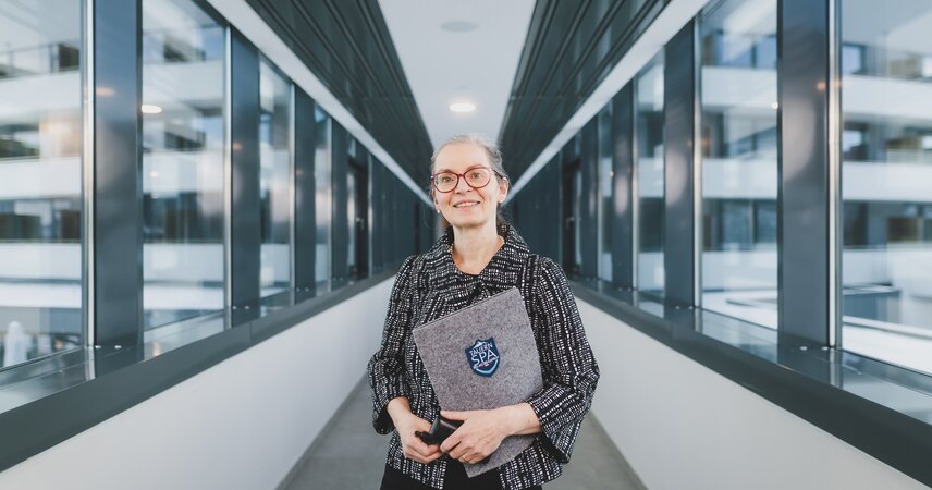 Lächelnde Frau mit Ordner in modernem Glasgang