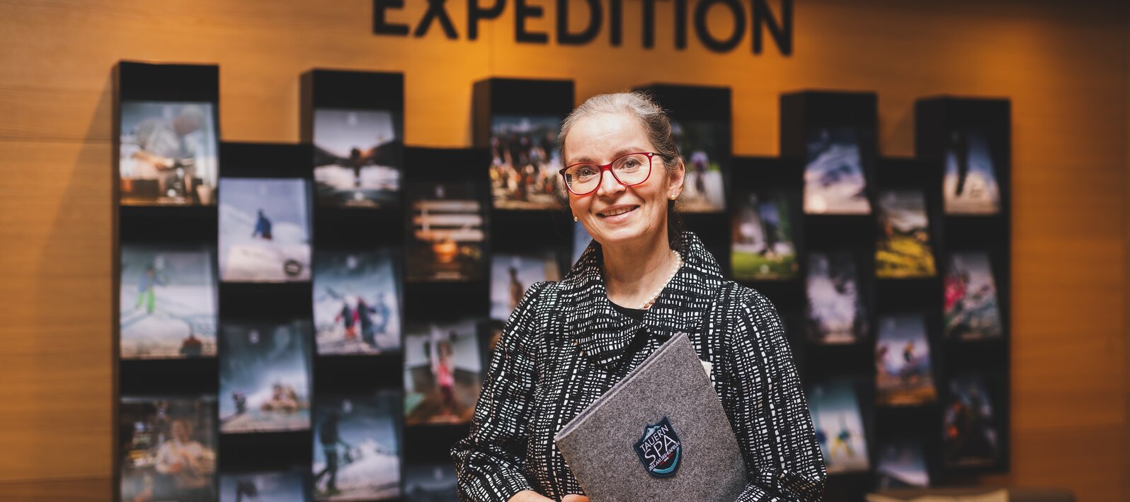 Lächelnde Frau mit Brille vor Ausstellungswand