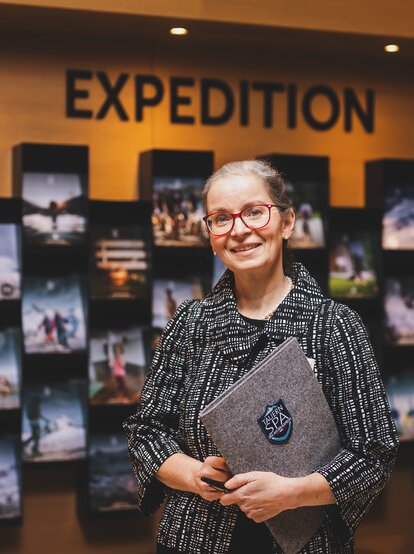 Lächelnde Frau mit Brille vor Ausstellungswand