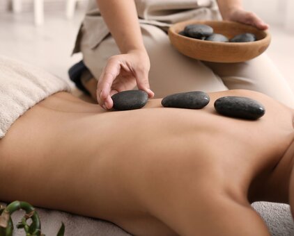 Hot stone massage on the back with dark stones and hands of a masseuse | © africa-studio.com (Olga Yastremska and Leonid Yastremskiy)