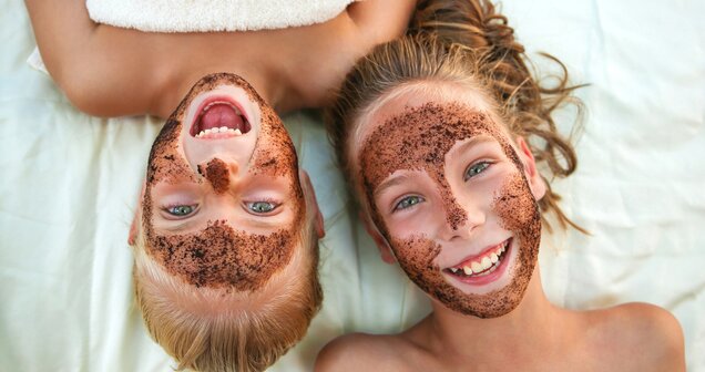 Two laughing children with face masks lying next to each other | © ©Victoria М - stock.adobe.com