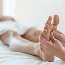 Foot reflexology massage: Hands massage a foot on a white couch | © lOvE lOvE
