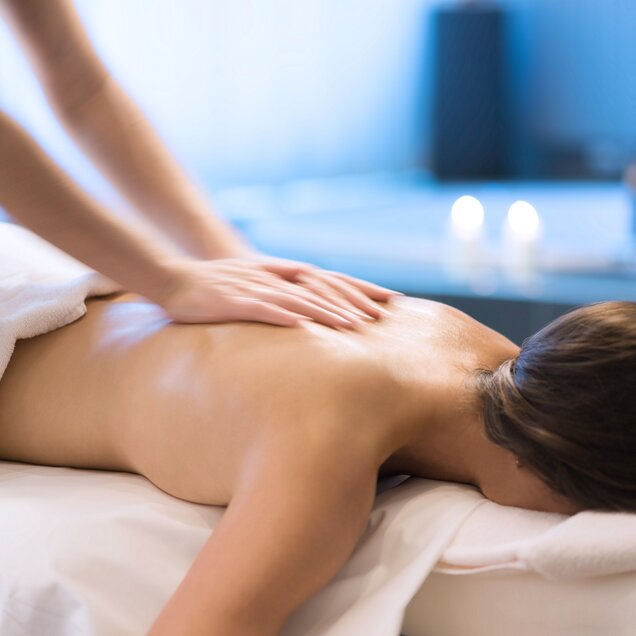 Woman lying on massage table, hands massaging her back