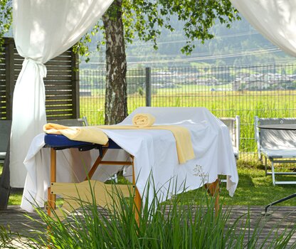 Outdoor massage table under a gazebo with white curtains
