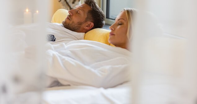 Couple relaxing in bathrobes on loungers in spa