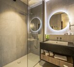 Modern bathroom with shower, sink and illuminated round mirrors